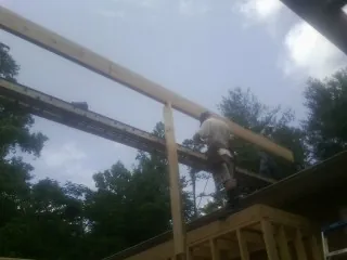 Carpenter setting a ridge beam over a new addition frame — Ice Dam Removal by Roofing Brothers in Holley