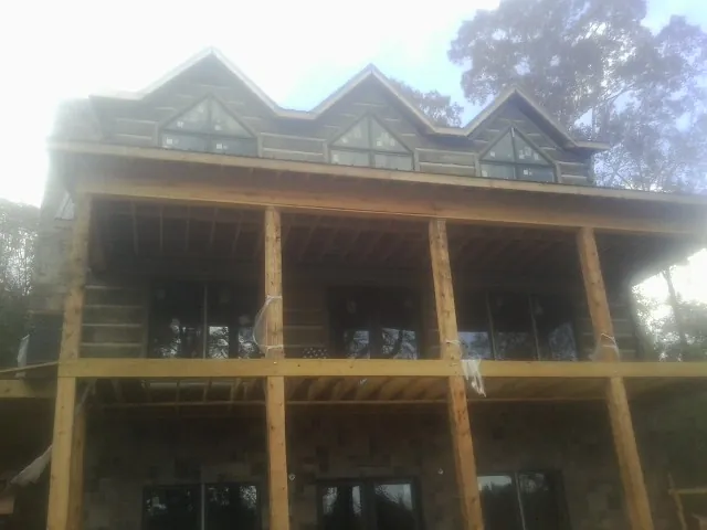 Dormers and porch framing on a large log home under construction — Roof Coating work by our crew in Holley
