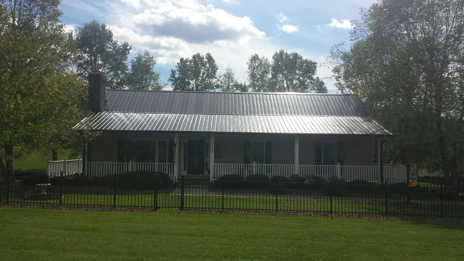 Gray metal roof on a brick ranch with a full width front porch — Gutter Guard Installation work by our crew in Holley