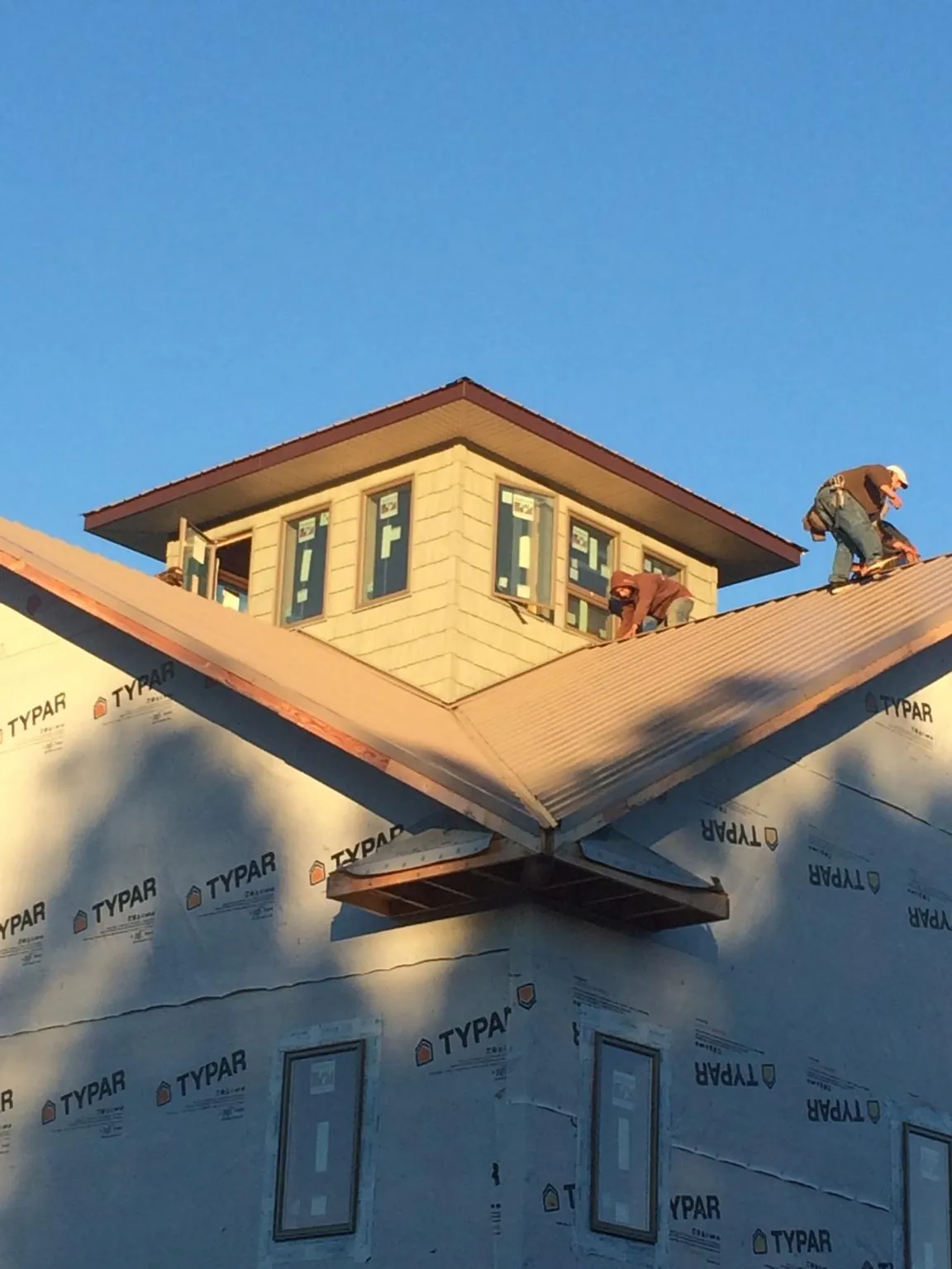 Roofers working around a rooftop cupola on a new metal roof at sunset — Roof Waterproofing in Holley by Roofing Brothers